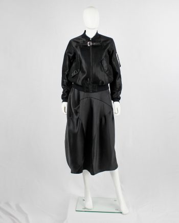 Noir Kei Ninomiya black bomber jacket with belted strap across the chest