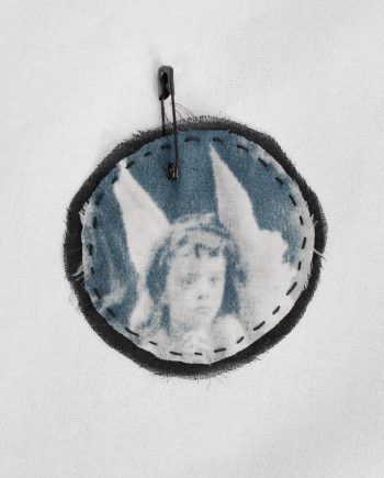 Ann Demeulemeester circle brooch with cherub print stitched onto black silk — fall 2005